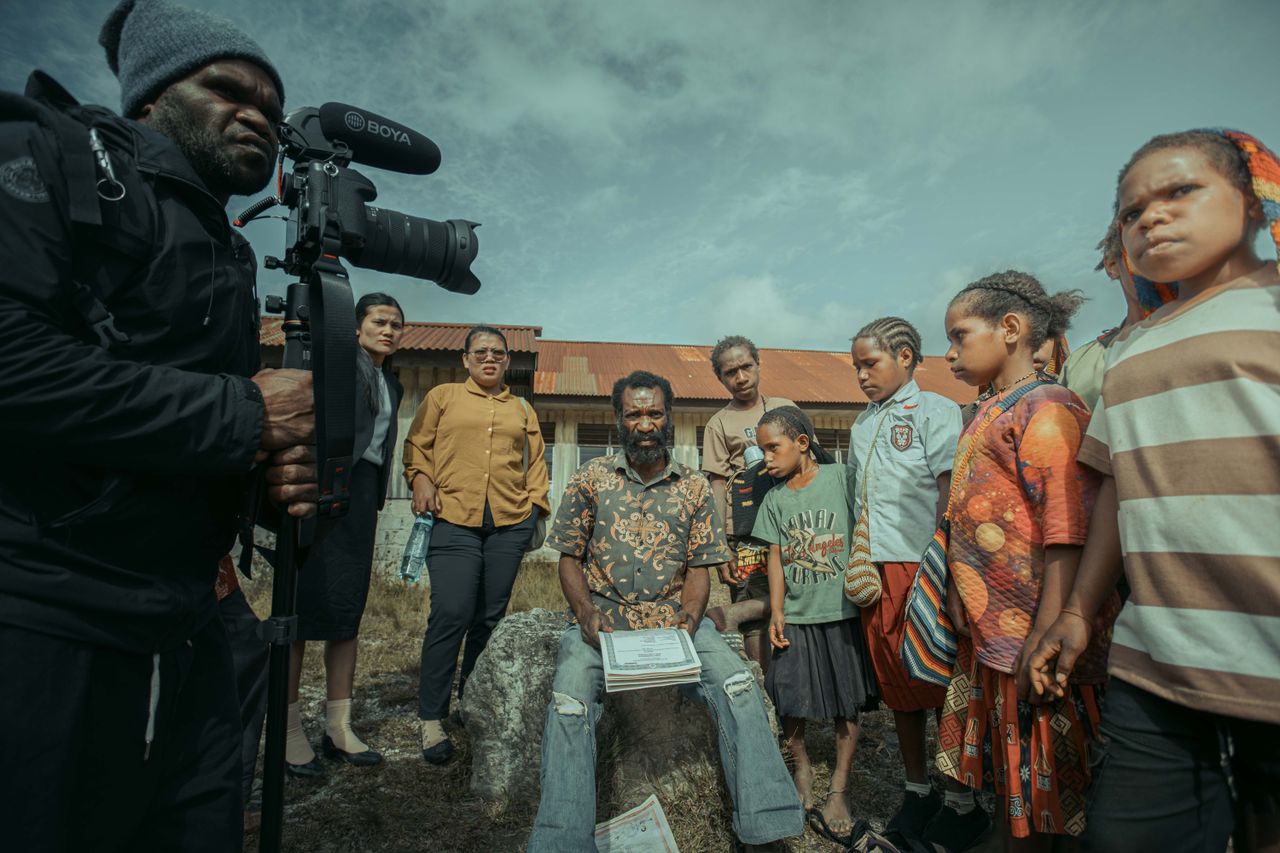 A filmmaker capturing a diverse group of people outdoors, emphasizing community and storytelling.